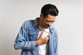 Young Asian man touching his chest where he feels pain due to heart attack problem. - PhotoDune Item for Sale