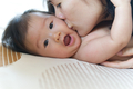 Close up shot from side view while mother kissing on kid's cheek. - PhotoDune Item for Sale