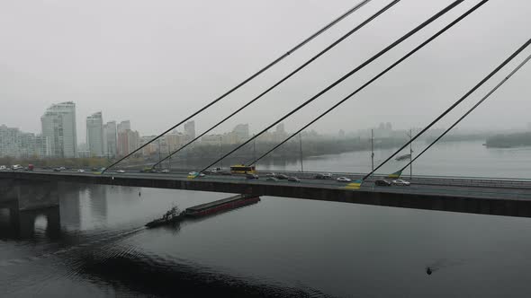 Industrial metropolis in fog with big concrete bridge and old barge floating on wide dirty river