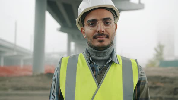 Portrait of Middle Eastern Builder Wearing Uniform Standing Outdoors in Building Site
