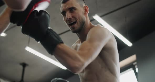 Low Angle Shot Fighter in Boxer Gloves is Practising His Strikes with Trainer in Slow Motion in the