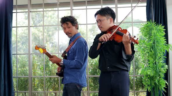 two asian men playing the violin classical instrument and guitar