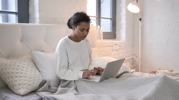 Tired Young African Girl with Neck Pain Working on Laptop in Bed