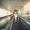 woman in hat with handbag standing on escalator line at airport - PhotoDune Item for Sale