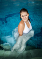 beautiful brunette woman in long white dress posing in swimming pool - PhotoDune Item for Sale