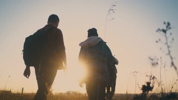 Joyful Men and Women Walk Along Grass Field at Sunset