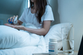 Asian unhappy sick girl in pajamas take medicine before sleep on bed. - PhotoDune Item for Sale