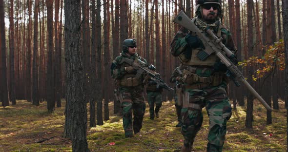 Squad of Four Fully Equipped Soldiers in Camouflage on a Reconnaissance Military Mission Aiming