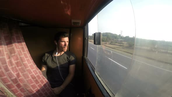 Man watching cityscape through train window during ride.