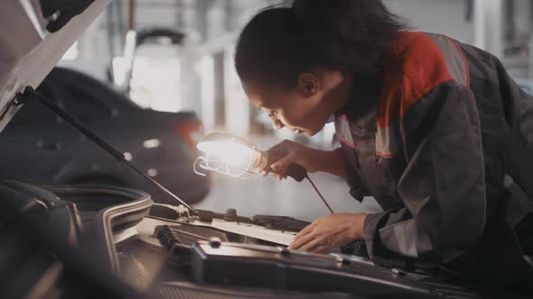 Female Auto Mechanic Looking under Hood of Car