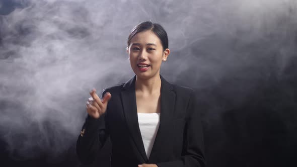 Asian Speaker Woman In Business Suit Showing Index Fingers Up While Speaking On Stage