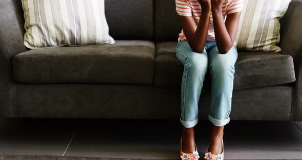 Upset girl sitting on sofa in corridor