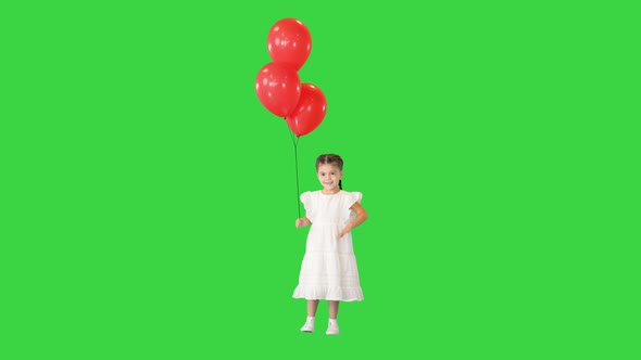 Adorable Little Girl Holds Tightly To a Large Bunch of Helium Balloons Walking on a Green Screen