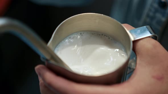 Barista steaming milk. barista whips milk in a pitcher with hot steam from coffee machine.