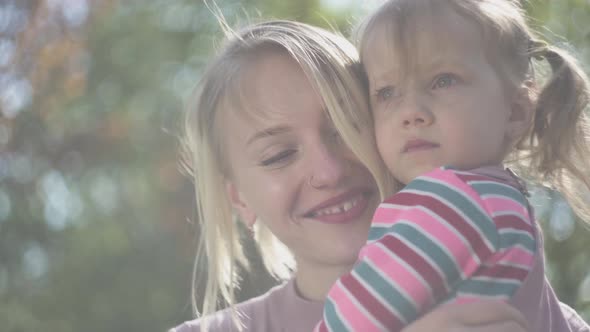 Portrait of Young Mother and Amazing Blond Daughter at Mothers Hands