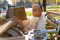 Serious woman lying on bicycle and reading book - PhotoDune Item for Sale
