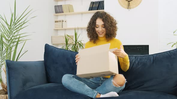 Excited Mixed Race Woman Opens Delivery Package Looking Inside