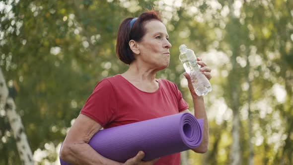 Elderly Woman with Yoga Mat Drinks Water