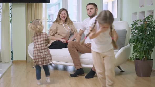 Happy Caucasian Woman Sitting on Couch Looking at Children Spinning in Slow Motion As Man Scolding