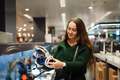 Cheerful young woman buying new headphones in tech store department - PhotoDune Item for Sale