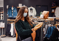 Young woman with loose long hair and face mask making seasonal purchases of clothes - PhotoDune Item for Sale