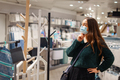 Young woman in face mask standing choosing coat rack, buying wooden hanger in shopping mall - PhotoDune Item for Sale