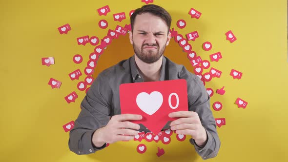 Man on an Isolated Yellow Background Holds a Sign in the Form of a Heart He is Upset That He Has