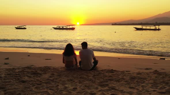 Two people sunbathe on perfect seashore beach voyage by blue water with white sandy background of Gi