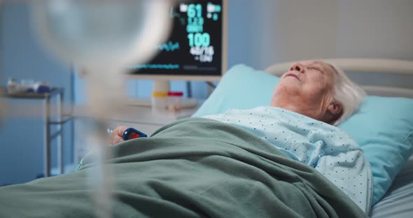 Aged Female Patient with Iv Drip Lying in Bed in Hospital Room