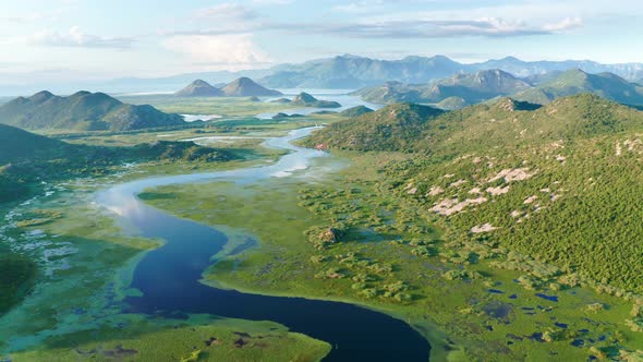 Bends and curves of blue river flowing through green valley toward distant mountains. 