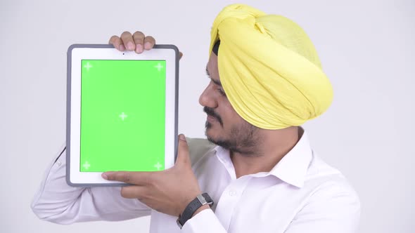 Face of Happy Bearded Indian Sikh Businessman Showing Digital Tablet