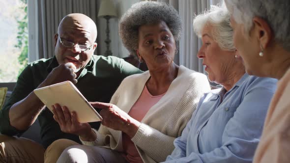 Group of diverse senior people using digital tablet together at home