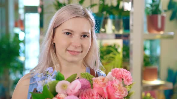 Florist Smiles and Shows Pink Flowers Bouquet at Camera