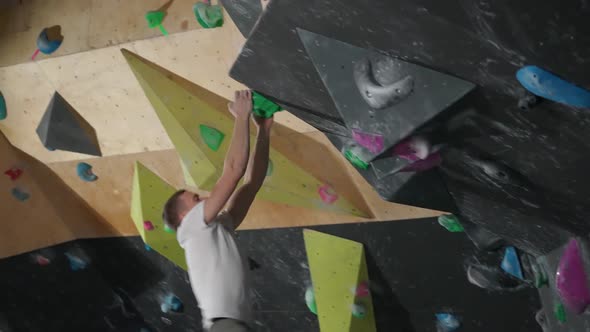 Moving Up Young Climber Training on a Climbing Wall Practicing Rockclimbing and Makes a Jump