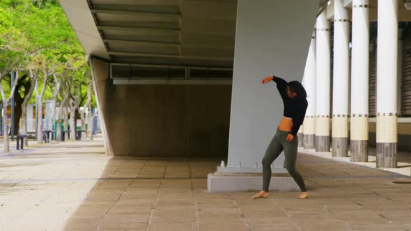 Female dancer dancing under a bridge in the city 4k