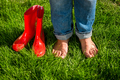 barefoot girl standing next red garden gumboots on grass - PhotoDune Item for Sale
