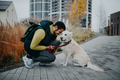 Happy young man squatting and embracing his dog during walk outdoors in city - PhotoDune Item for Sale