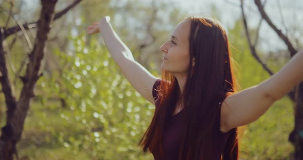 Young Woman Enjoys Nature in the Forest Raises Her Hands Up From Pleasure