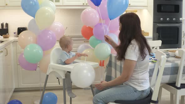 Mother and Baby are Preparing to Celebrate Children Birthday Blowing Up Balloons to Decorate Home