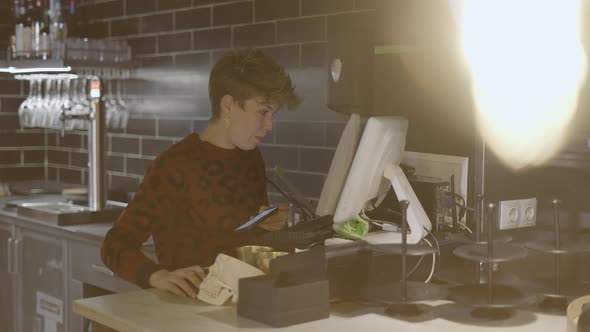 Female Restaurant Owner Stands and Talks By Computer By Kitchen