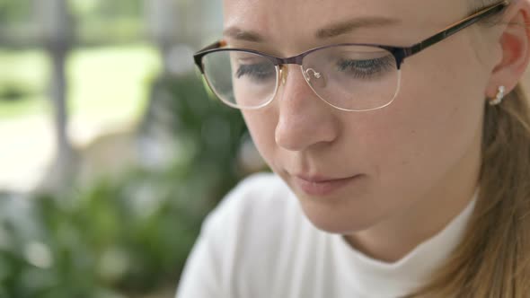 Pensive Woman in Eyeglasses Looks at Something Close View