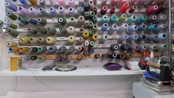 Set of Colored Threads for Sewing on Reels on the Wall in the Sewing Workshop