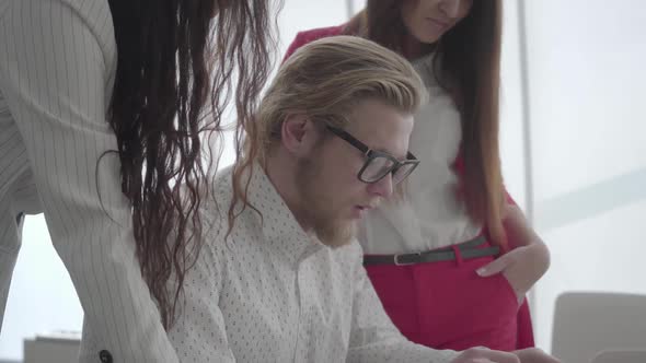 Portrait Successful Blond Man in Glasses Sitting in a Light Comfortable Office with Netbook