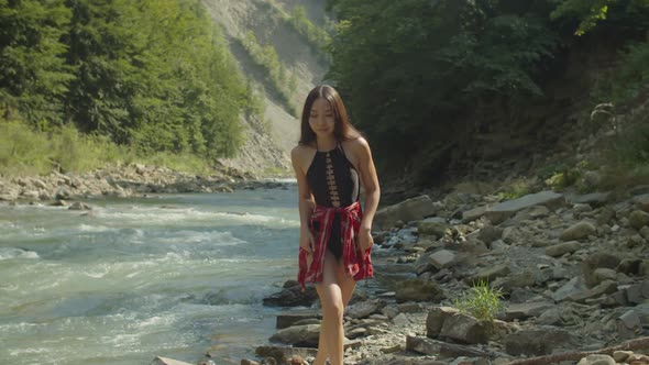Elegant Lovely Asian Woman in Swimsuit Gracefully Walking Along Mountain Rocky Riverbank