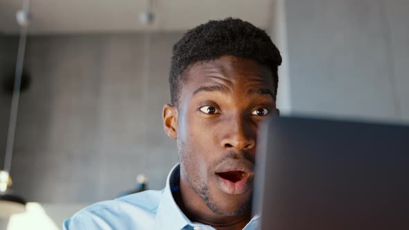 Happy african american man receiving good news using internet at home