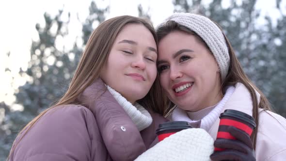 Portrait of Two Happy Girls in a Snowy Park on a Frosty Winter Day