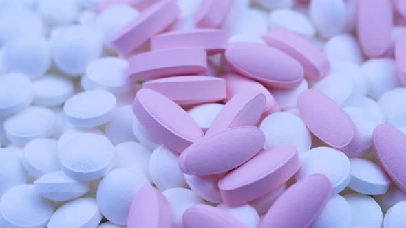 Pink Oval Pills Lie with Small White Round Medicines. Close Up Rotation alt