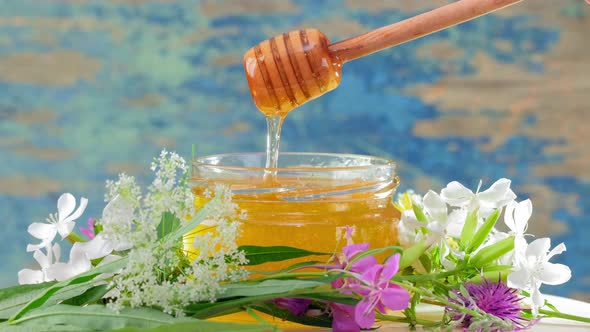 Honey in Glass Jar with Honey Dipper Over Rustic Wooden Background