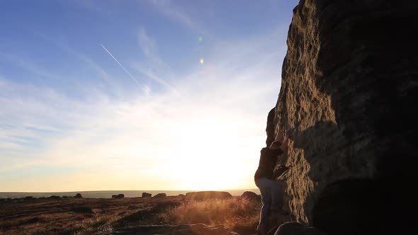 Silhouette of a man climbing boulders while bouldering.