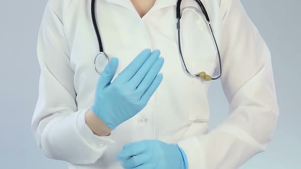 Hospital employee wearing medical gloves, making funny scary gestures, joking